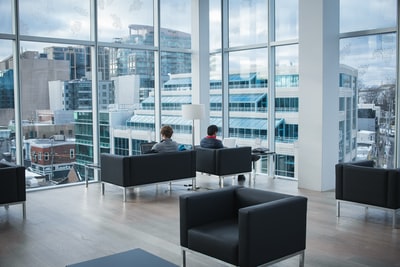 Two people sit by the window of the black sofa
